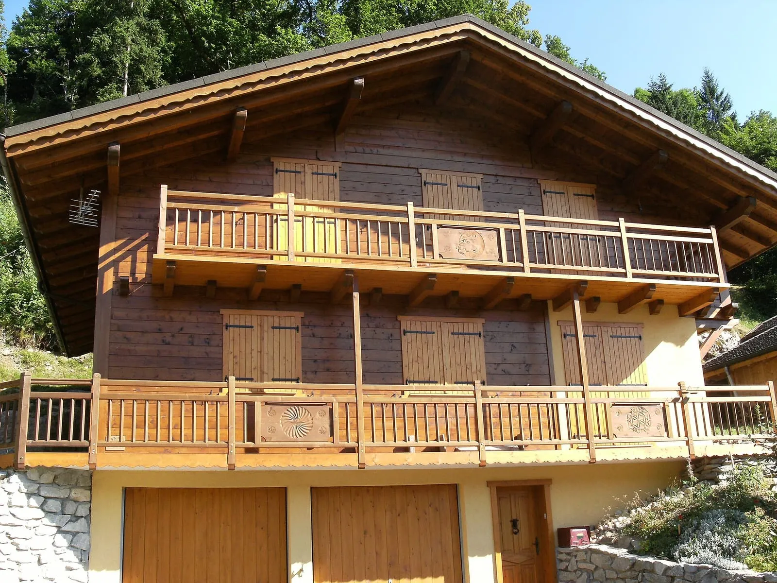 Façade d’un grand chalet en bois aux balcons ajourés sur deux niveaux