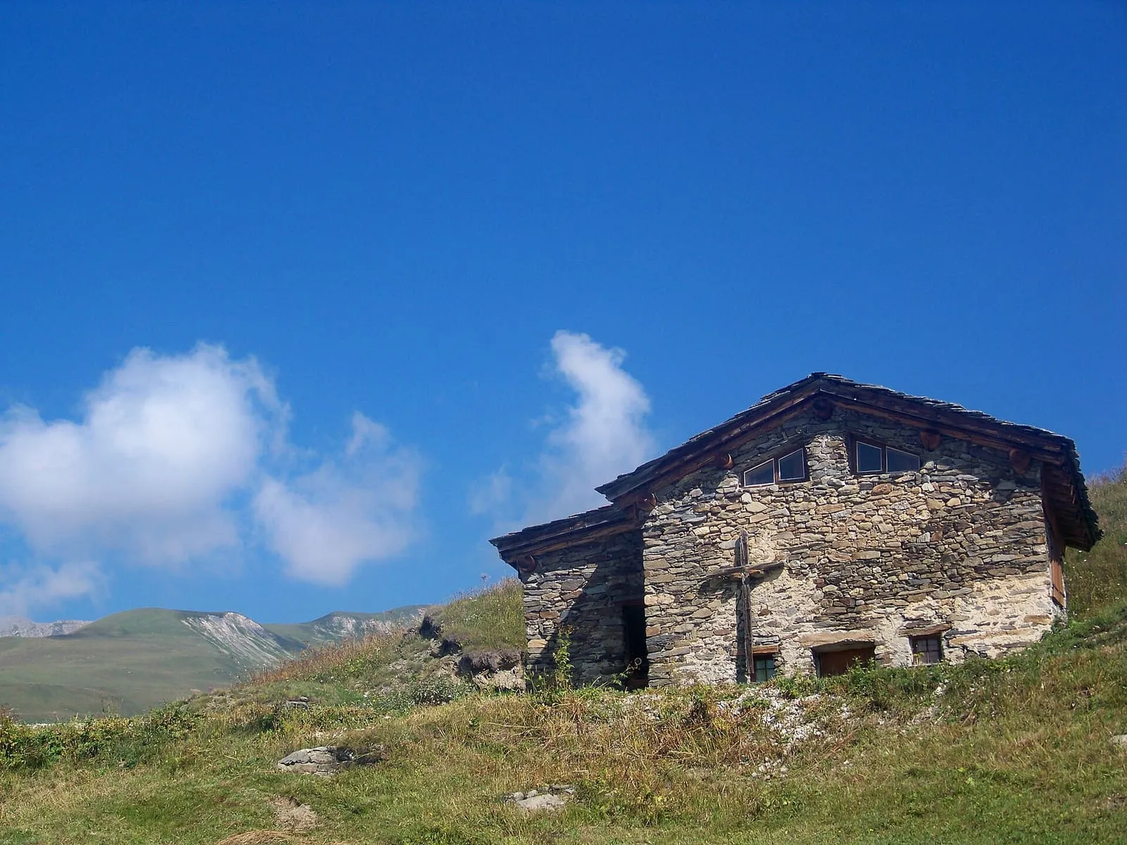 Chalet d’alpage en pierre sèche et toit de lauzes sous un ciel bleu
